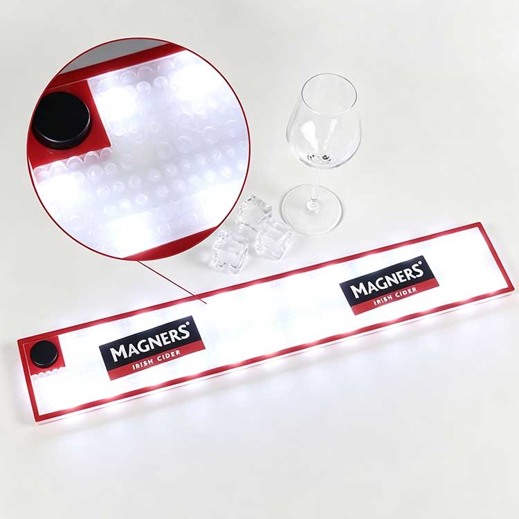 Close-up detail shot of commercial LED bar runner non-slip bubble spill control texture and side battery power switch knob, illuminated Magners branded bar spill mat for home and commercial bar use