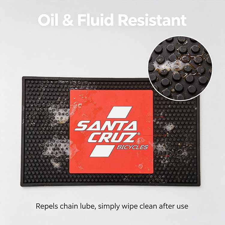 Oil and fluid resistant rubber benchtop mat showing liquid repellency against bike chain lube and workshop cleaners