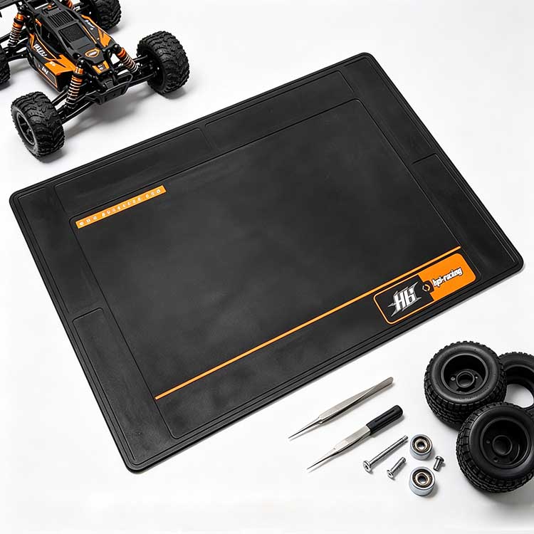 Spacious black rubber pit mat holding RC buggy tires, bearings, and precision tuning tools