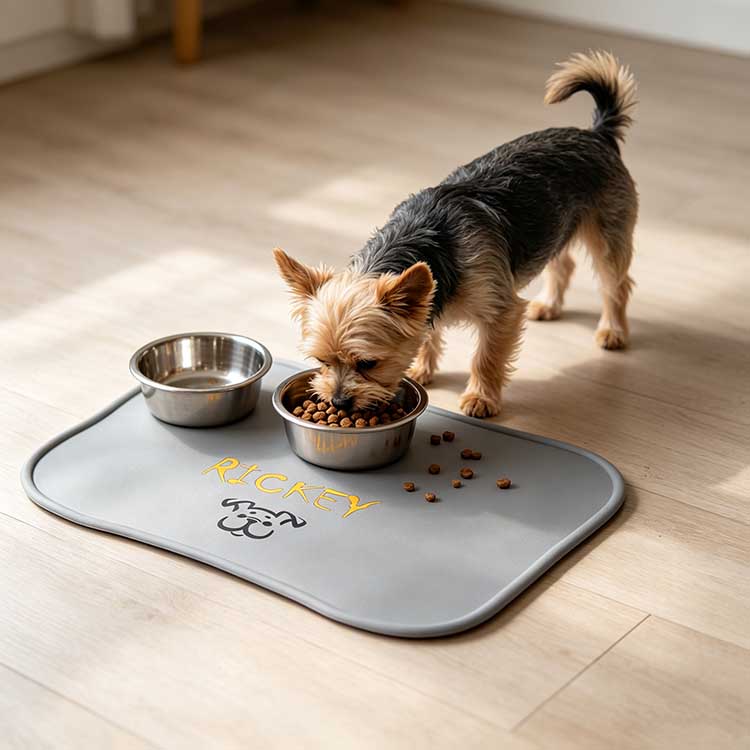 Yorkie eating from a custom silicone pet placemat with personalized name and bowl holders.