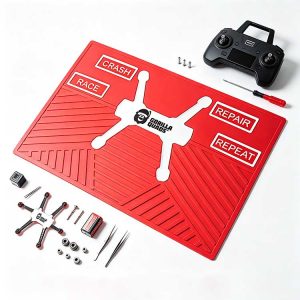 Red non-slip tech mat for FPV drone assembly with remote, battery, and drone parts