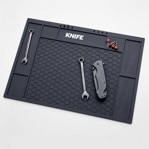 Black hexagonal honeycomb knife tool mat with branding zone and storage slots.